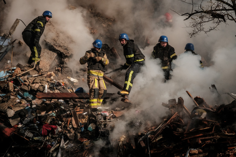 Bombeiros trabalham junto aos destroços no prédio destruído por um drone na capital ucraniana